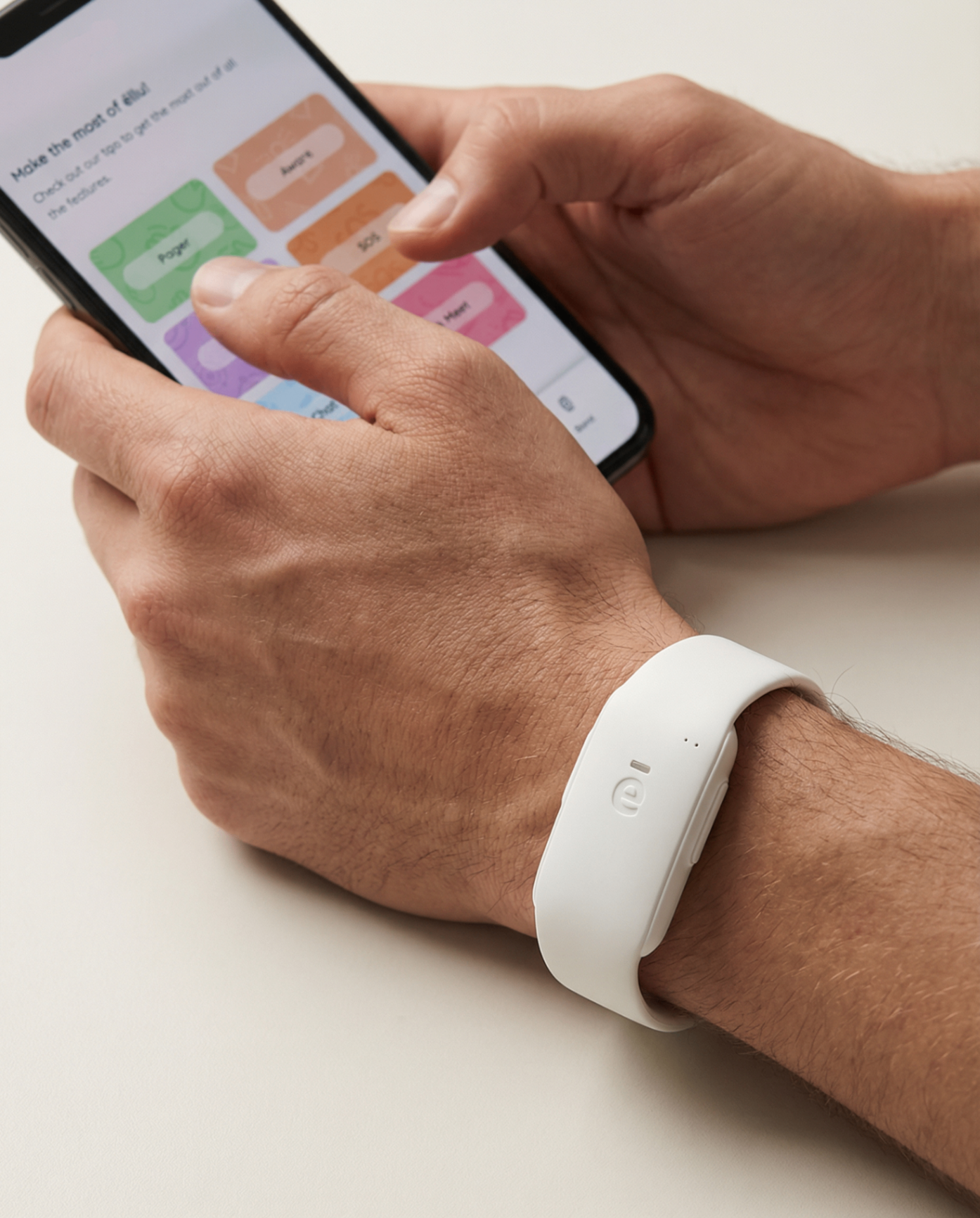 Hands using the ellu companion app on a phone while wearing a white ellu wristband