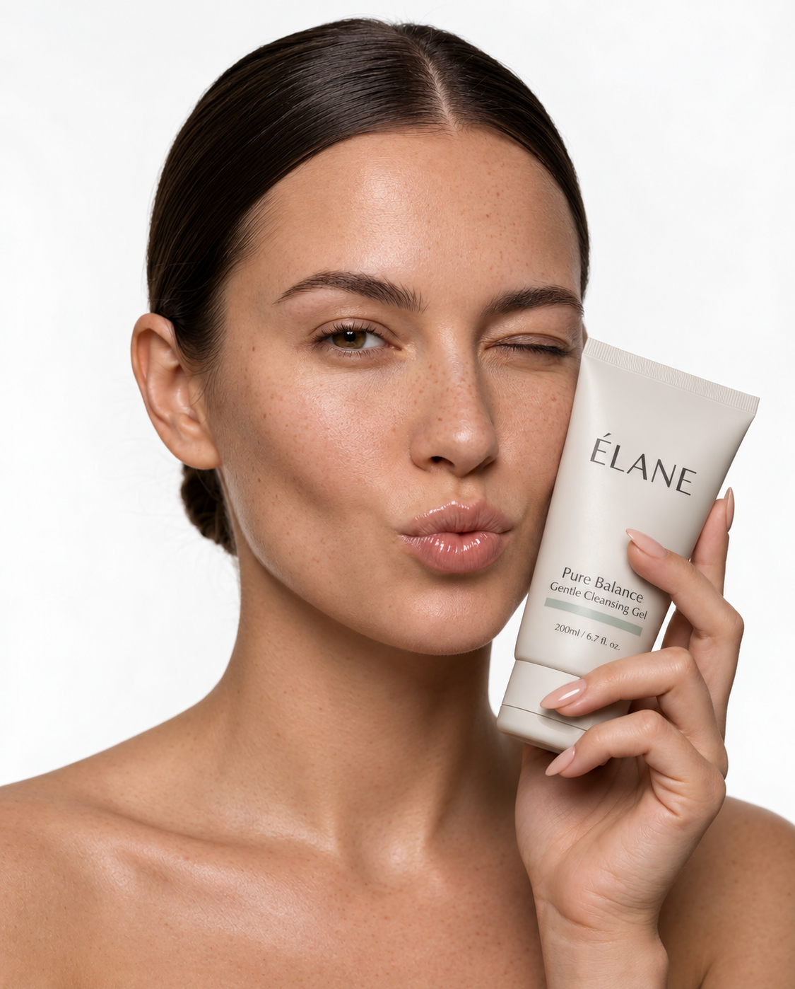 Model winking while holding an ÉLANE Pure Balance cleansing gel tube beside her face